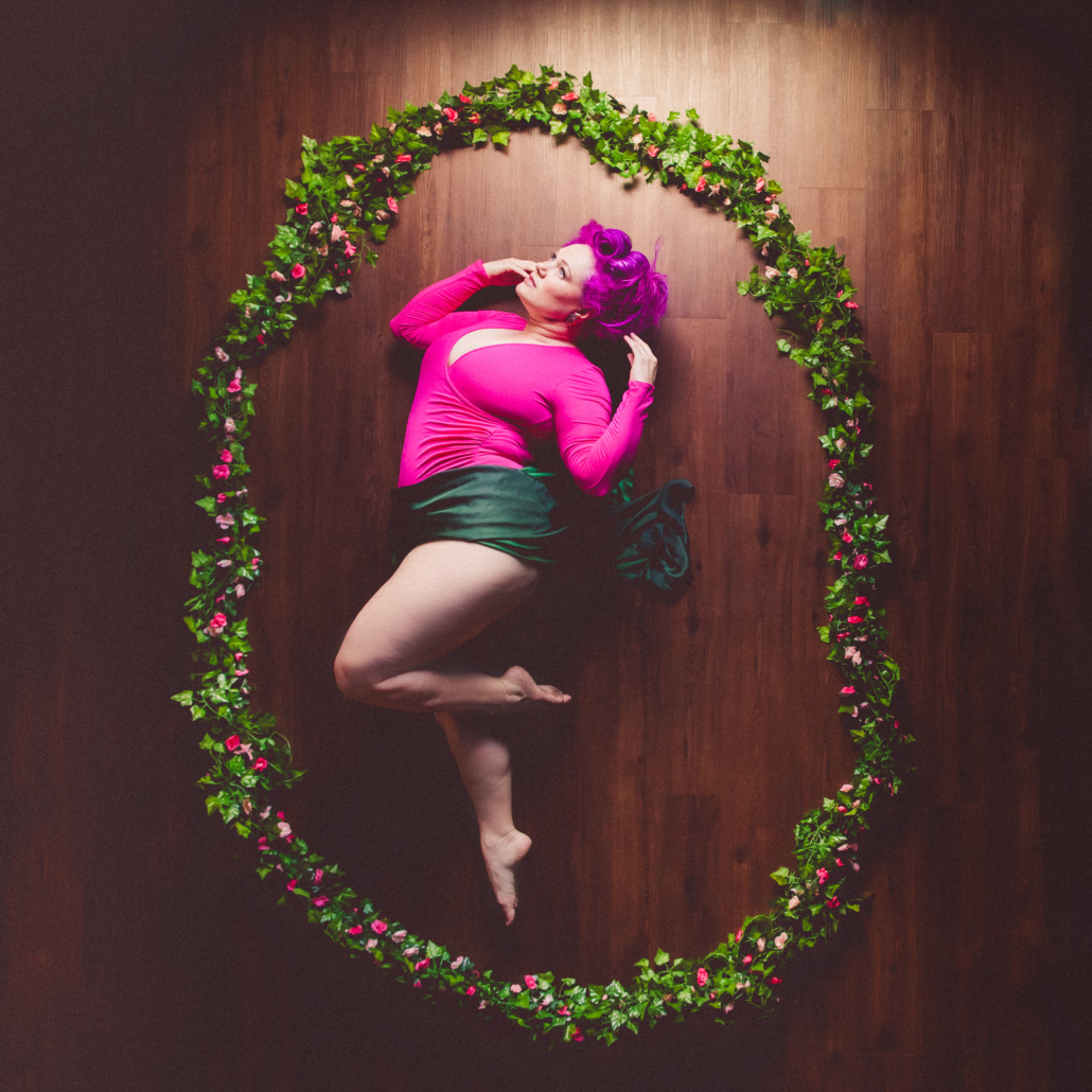 the mell bell wearing pink and green inside a garland of flowers