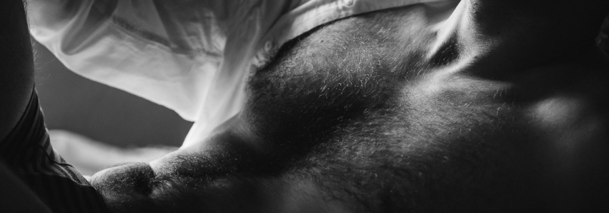 black and white close up of a male in a white unbuttoned shirt