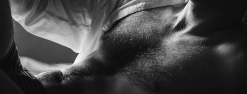 black and white close up of a male in a white unbuttoned shirt