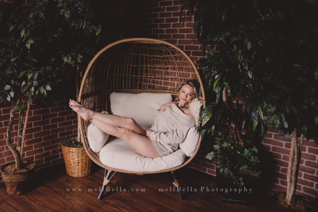 woman in cream sweater sitting on egg chair with feet propped up