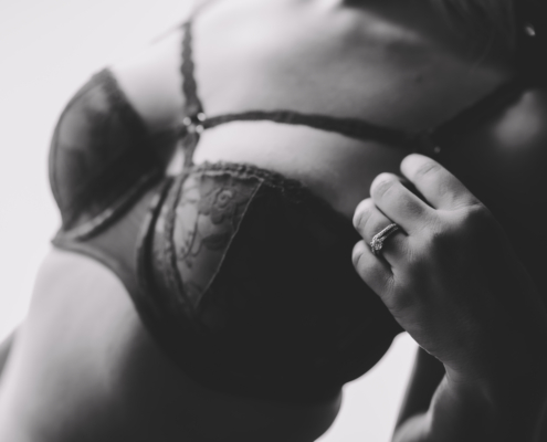 black and white close up of a woman's chest with her left hand and weddings bands in focus