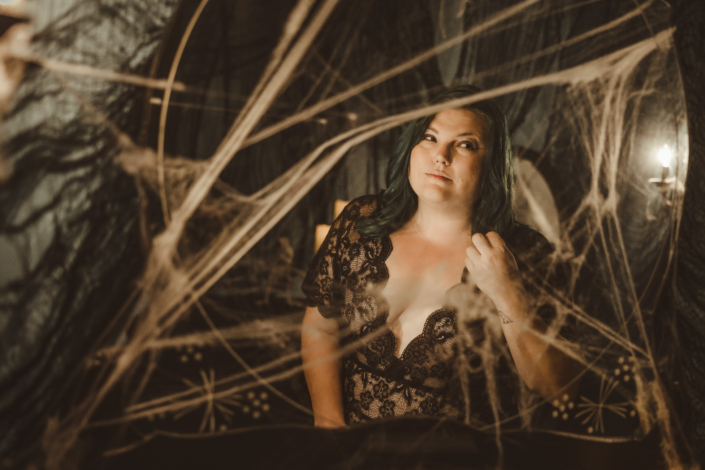 woman looking into an antique mirror covered in spider webs